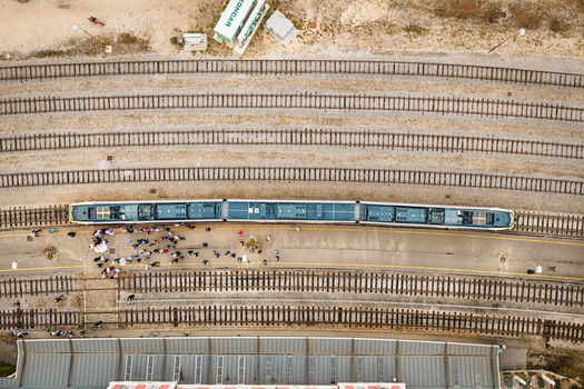 Aerial view of a train stopped at a station platform with passengers waiting surrounded by multiple railway tracks and the roof of a station building in Buzet Istria County Croatia.