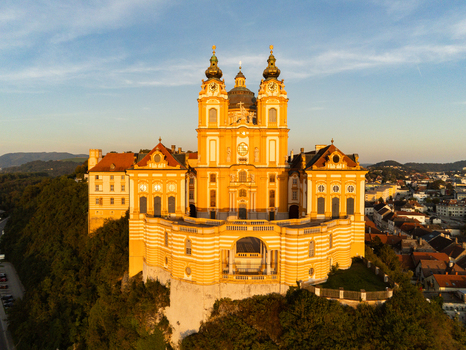 Aerial view of Melk Abbey a magnificent baroque monastery perched on a rocky outcrop overlooking the town illuminated by warm golden sunset light in Melk Niederosterreich Austria. Aerial view of Melk Abbey a magnificent baroque monastery perched on a rocky outcrop overlooking the town illuminated by warm golden sunset light in Melk Niederosterreich Austria.