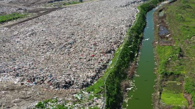 Aerial view of landfill site next to polluted canal in Russia.