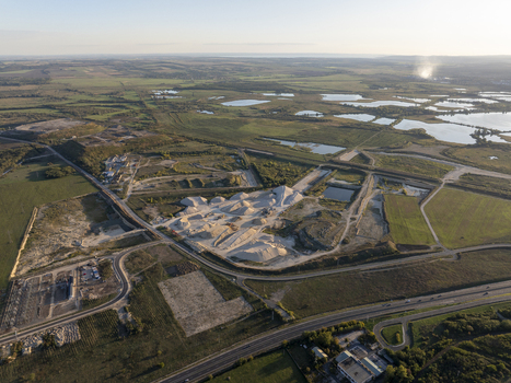 Aerial view of the abandoned Inota Power Plant cooling towers surrounded by industrial gravel piles ponds and green fields near a highway in Varpalota Hungary. Aerial view of the abandoned Inota Power Plant cooling towers surrounded by industrial gravel piles ponds and green fields near a highway in Varpalota Hungary.