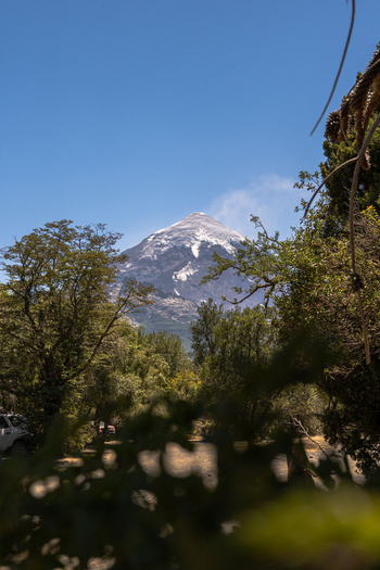View of Lanin volcano with its snow capped peak rising above the surrounding forest under a clear blue sky in Huiliches Department Neuquen Province Argentina. View of Lanin volcano with its snow capped peak rising above the surrounding forest under a clear blue sky in Huiliches Department Neuquen Province Argentina.