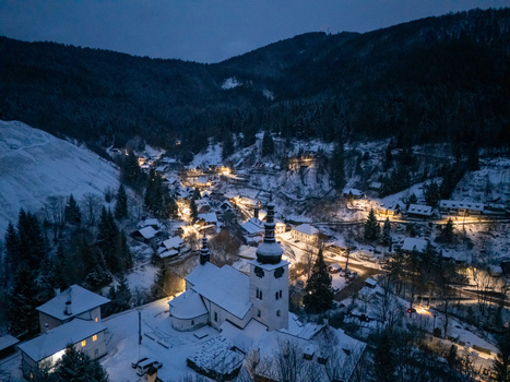 Aerial view of the historic village of Spania Dolina with its illuminated church and snow covered rooftops nestled in a forested valley at night Spania Dolina Banska Bystrica Region Slovakia. Aerial view of the historic village of Spania Dolina with its illuminated church and snow covered rooftops nestled in a forested valley at night Spania Dolina Banska Bystrica Region Slovakia.