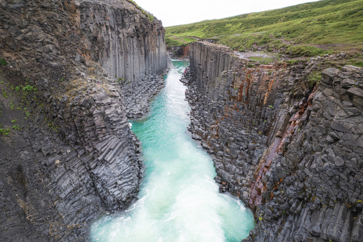 Aerial view of Studlagil Canyon with basalt columns and a turquoise river flowing through the rocky valley Eiriksstadhir Mulathing Iceland. Aerial view of Studlagil Canyon with basalt columns and a turquoise river flowing through the rocky valley Eiriksstadhir Mulathing Iceland.