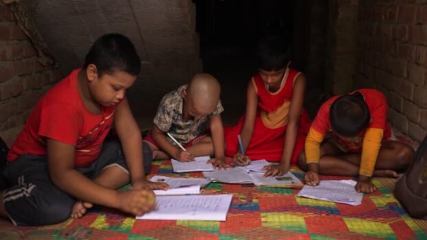 View of children studying and writing in notebooks Bangladesh.