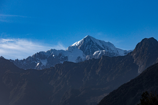 View of snow capped peak rises majestically against the azure sky casting long shadows over the rugged terrain Lake Matheson New Zealand. View of snow capped peak rises majestically against the azure sky casting long shadows over the rugged terrain Lake Matheson New Zealand.