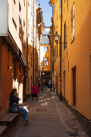 Stockholm Sweden 02 May 2026 View of the narrow Yxsmedsgrand alleyway with historic yellow buildings cobblestone pavement and people walking under the bright sunlight in Gamla Stan.