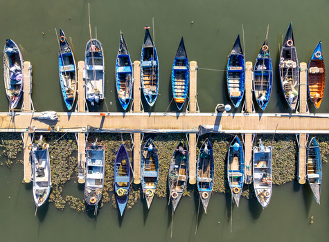 Aerial view of colorful boats moored along a weathered pier reflecting in the tranquil water creating a mosaic of maritime charm Kochi India. Aerial view of colorful boats moored along a weathered pier reflecting in the tranquil water creating a mosaic of maritime charm Kochi India.