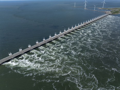 Aerial view of the Eastern Scheldt Storm Surge Barrier spanning the Oosterschelde estuary with turbulent water and wind turbines in Vrouwenpolder Zeeland Netherlands. Aerial view of the Eastern Scheldt Storm Surge Barrier spanning the Oosterschelde estuary with turbulent water and wind turbines in Vrouwenpolder Zeeland Netherlands.