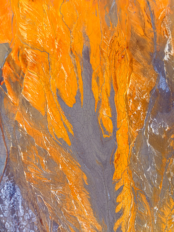 Aerial view of the Rio Tinto river delta showing vibrant orange and grey mineral rich sediment patterns and cracked earth textures in Andalusia Spain. Aerial view of the Rio Tinto river delta showing vibrant orange and grey mineral rich sediment patterns and cracked earth textures in Andalusia Spain.