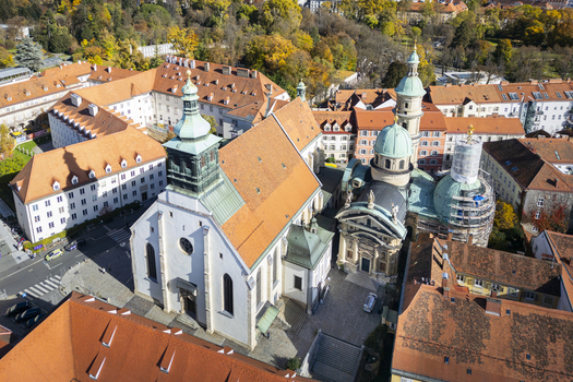 Aerial view of the Franciscan Church standing majestically amidst the cityscape its red tile roof contrasting with the green domes Graz Styria Austria.