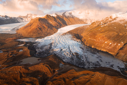 Aerial view of Svinafellsjokull glacier with rugged mountains glacial lake and golden hour light in Sveitarfelagid Hornafjordur Iceland. Aerial view of Svinafellsjokull glacier with rugged mountains glacial lake and golden hour light in Sveitarfelagid Hornafjordur Iceland.