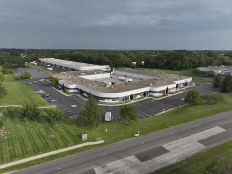 Aerial view of a commercial building complex with a central courtyard parking lot and pond surrounded by green space in Indianapolis Indiana United States. Aerial view of a commercial building complex with a central courtyard parking lot and pond surrounded by green space in Indianapolis Indiana United States.