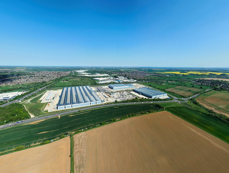Aerial view of Symmetry Park logistics hub featuring large modern warehouses and distribution centers surrounded by green fields and the A14 road Kettering England United Kingdom. Aerial view of Symmetry Park logistics hub featuring large modern warehouses and distribution centers surrounded by green fields and the A14 road Kettering England United Kingdom.