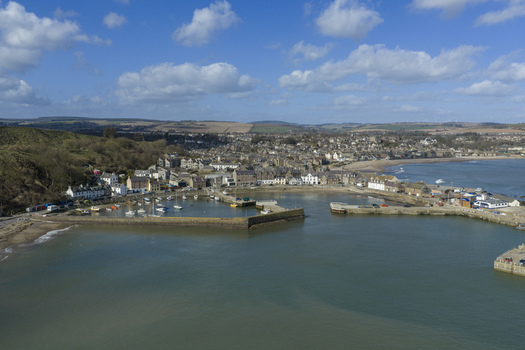 Aerial view of Stonehaven harbor with boats moored by the stone pier and the historic town under a blue sky Stonehaven Scotland United Kingdom. Aerial view of Stonehaven harbor with boats moored by the stone pier and the historic town under a blue sky Stonehaven Scotland United Kingdom.
