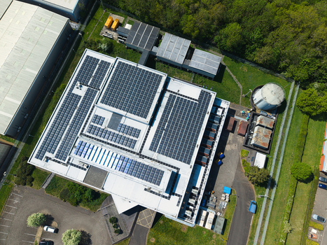 Aerial view of a modern data centre building featuring extensive solar panel installations on the roof surrounded by lush green trees in Wellingborough England United Kingdom. Aerial view of a modern data centre building featuring extensive solar panel installations on the roof surrounded by lush green trees in Wellingborough England United Kingdom.
