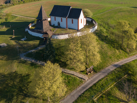 Aerial view of the historic Church of St. Martin with its wooden bell tower and circular stone wall on a green hill in Cerin Banskobystricky kraj Slovakia. Aerial view of the historic Church of St. Martin with its wooden bell tower and circular stone wall on a green hill in Cerin Banskobystricky kraj Slovakia.