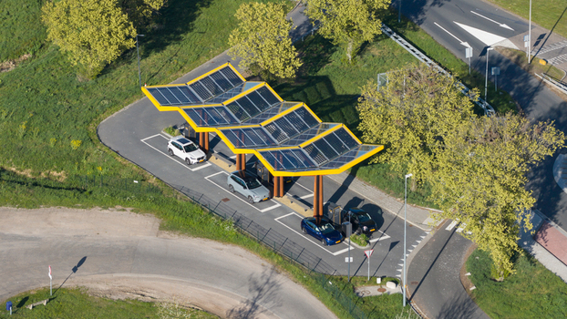 Bant Netherlands 23 April 2026 Aerial view of Fastned Charging Station with its yellow solar paneled roof electric vehicles parked and surrounding green trees under bright daylight. Bant Netherlands 23 April 2026 Aerial view of Fastned Charging Station with its yellow solar paneled roof electric vehicles parked and surrounding green trees under bright daylight.