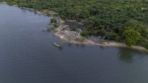 Aerial view of a ruined stone structure on a narrow peninsula surrounded by lush tropical forest and palm trees along the waterfront Badagry Lagos Nigeria. Aerial view of a ruined stone structure on a narrow peninsula surrounded by lush tropical forest and palm trees along the waterfront Badagry Lagos Nigeria.