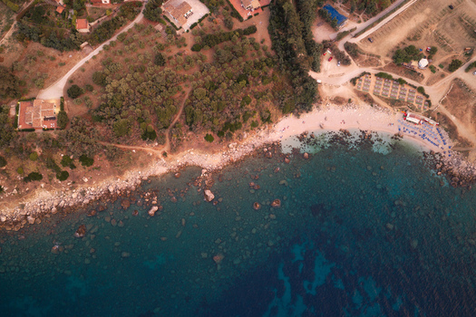 Aerial view of Riserva Naturale Orientata dello Zingaro featuring rocky coastline turquoise sea Mediterranean vegetation and nearby villas in San Vito Lo Capo Sicilia Italy. Aerial view of Riserva Naturale Orientata dello Zingaro featuring rocky coastline turquoise sea Mediterranean vegetation and nearby villas in San Vito Lo Capo Sicilia Italy.