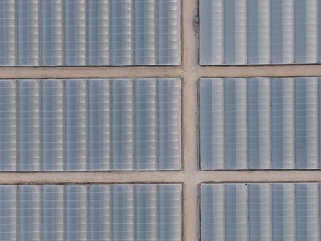 Aerial view of large agricultural greenhouses with plastic coverings and dirt paths in a geometric layout in Paestum Campania Italy.