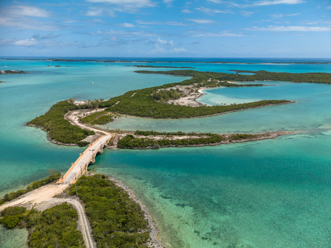 Aerial view of the bridge leading to Crab Cay surrounded by vibrant turquoise waters and lush green vegetation in Exuma Exuma The Bahamas. Aerial view of the bridge leading to Crab Cay surrounded by vibrant turquoise waters and lush green vegetation in Exuma Exuma The Bahamas.