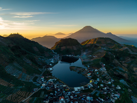 Aerial view of Telaga Cebong lake surrounded by terraced vegetable fields and mountains in Kecamatan Kejajar Jawa Tengah Indonesia.