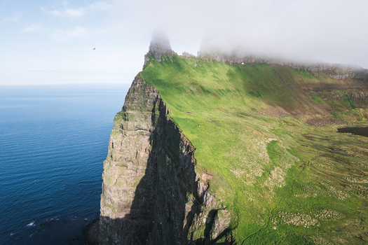 Aerial view of the dramatic Hornstrandir Nature Reserve cliffs dropping into the blue ocean under a misty sky Isafjordur Isafjardarbaer Iceland. Aerial view of the dramatic Hornstrandir Nature Reserve cliffs dropping into the blue ocean under a misty sky Isafjordur Isafjardarbaer Iceland.