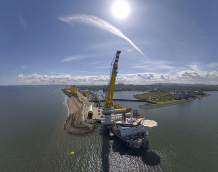 Aerial view of a large wind turbine installation vessel docked at the port of Leith with industrial cranes and turbine components under a bright sun in Edinburgh Scotland United Kingdom. Aerial view of a large wind turbine installation vessel docked at the port of Leith with industrial cranes and turbine components under a bright sun in Edinburgh Scotland United Kingdom.