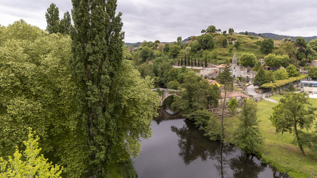 Aerial view of Ponte de Vilanova stone bridge crossing the Arnoia River surrounded by lush green trees and historic buildings Allariz Ourense Spain. Aerial view of Ponte de Vilanova stone bridge crossing the Arnoia River surrounded by lush green trees and historic buildings Allariz Ourense Spain.