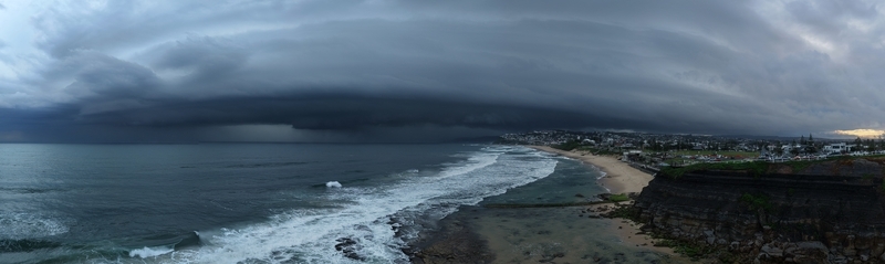 Aerial view of a menacing storm front looms over Newcastle Beach casting a dark shadow on the waves and coastline Newcastle New South Wales Australia.