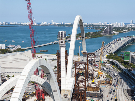 Aerial view of the vibrant juxtaposition of the new Fountain Bridge construction against the skyline with Biscayne Bay shimmering in the background Miami Florida USA. Aerial view of the vibrant juxtaposition of the new Fountain Bridge construction against the skyline with Biscayne Bay shimmering in the background Miami Florida USA.