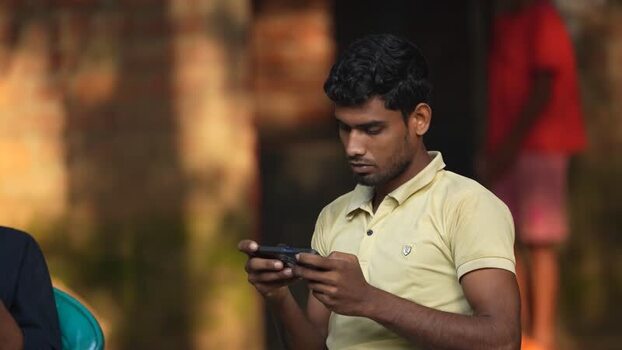 View of a young man using a smartphone in Bogura Bangladesh. View of a young man using a smartphone in Bogura Bangladesh.