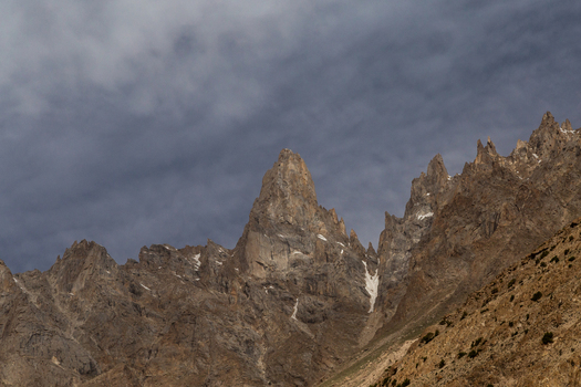 View of the rugged peaks of the Baltoro Glacier under a dramatic cloudy sky in the high altitude mountain landscape of Baltoro Gilgit Baltistan Pakistan.