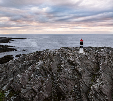 Aerial view of Hamningberg Lighthouse standing on rugged rocky cliffs overlooking the Barents Sea in Hamningberg Finnmark Norway. Aerial view of Hamningberg Lighthouse standing on rugged rocky cliffs overlooking the Barents Sea in Hamningberg Finnmark Norway.