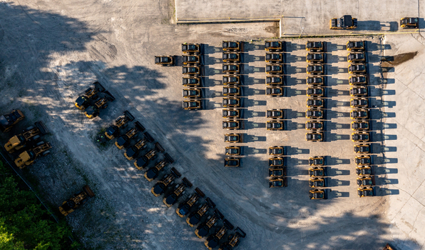 Aerial view of rows of yellow skid steer loaders parked in an organized gravel lot at a construction equipment depot near Noxon Road in LaGrange New York United States. Aerial view of rows of yellow skid steer loaders parked in an organized gravel lot at a construction equipment depot near Noxon Road in LaGrange New York United States.