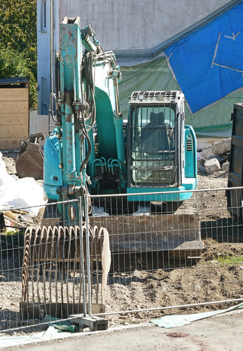 View of a teal excavator parked at a building demolition and road construction site in Garching Bavaria Germany. View of a teal excavator parked at a building demolition and road construction site in Garching Bavaria Germany.