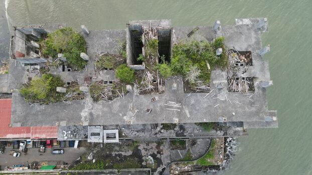 Aerial view of an abandoned concrete building roof overgrown with vegetation and debris situated along the coastline in Balikpapan East Kalimantan Indonesia. Aerial view of an abandoned concrete building roof overgrown with vegetation and debris situated along the coastline in Balikpapan East Kalimantan Indonesia.