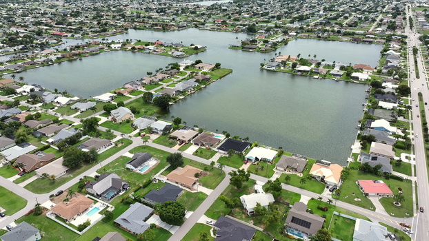Aerial view of residential houses with swimming pools and canals in the suburban neighborhood of Cape Coral Florida United States.