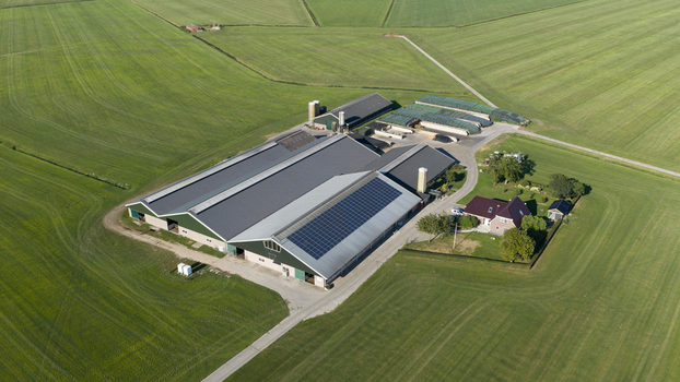 Aerial view of a large modern dairy farm with solar panels on the roof surrounded by vast green agricultural fields in Groningen Groningen Netherlands. Aerial view of a large modern dairy farm with solar panels on the roof surrounded by vast green agricultural fields in Groningen Groningen Netherlands.