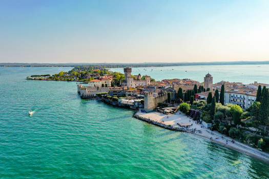Aerial view of Castello Scaligero di Sirmione and the historic town on the shores of Lake Garda with turquoise water in Sirmione Lombardia Italy.