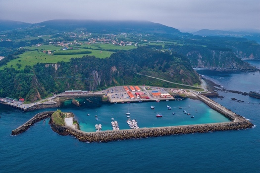 Aerial view of the historic port of Cudillero featuring a stone breakwater turquoise waters with moored boats and lush green cliffs under a misty sky Cudillero Asturias Spain. Aerial view of the historic port of Cudillero featuring a stone breakwater turquoise waters with moored boats and lush green cliffs under a misty sky Cudillero Asturias Spain.