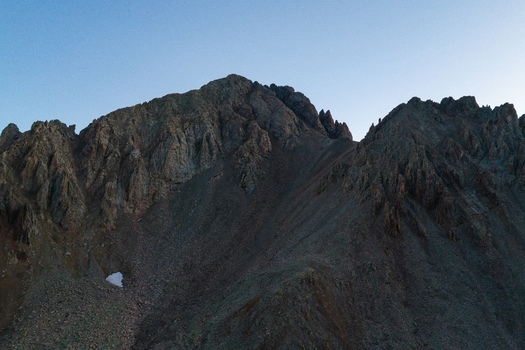 Aerial view of Mount Sneffels in the San Juan Mountains featuring rugged rocky peaks steep slopes and a small patch of snow in Ouray County Colorado United States. Aerial view of Mount Sneffels in the San Juan Mountains featuring rugged rocky peaks steep slopes and a small patch of snow in Ouray County Colorado United States.
