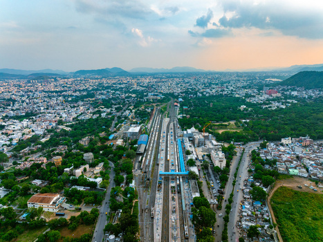 Aerial view of the railway station tracks stretching through the urban landscape of Udaipur surrounded by lush trees and distant hills in Udaipur Rajasthan India. Aerial view of the railway station tracks stretching through the urban landscape of Udaipur surrounded by lush trees and distant hills in Udaipur Rajasthan India.