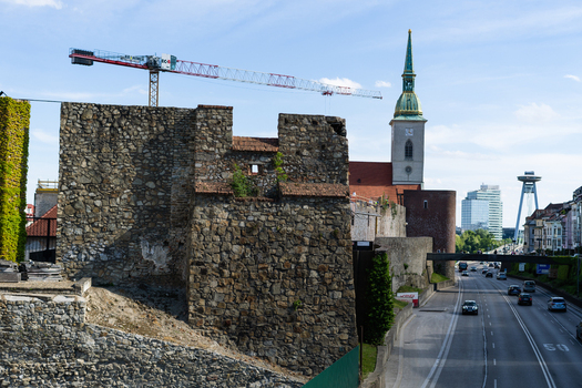 View of the historic stone city walls and St. Martin s Cathedral spire with a construction crane and traffic on the road Bratislava Bratislava Region Slovakia. View of the historic stone city walls and St. Martin s Cathedral spire with a construction crane and traffic on the road Bratislava Bratislava Region Slovakia.