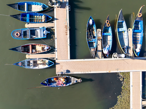 Aerial view of colorful boats moored at the Porta de Abrigo da Torreira their vibrant hues contrasting with the dark water Torreira Aveiro Portugal.