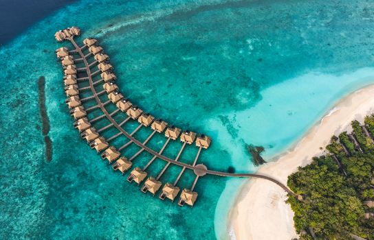 Aerial view of luxury overwater bungalows arranged along a wooden pier in a turquoise lagoon with a white sand beach Hoarafushi Haa Alif Atoll Maldives. Aerial view of luxury overwater bungalows arranged along a wooden pier in a turquoise lagoon with a white sand beach Hoarafushi Haa Alif Atoll Maldives.