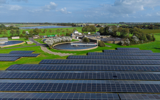 Aerial view of a water treatment plant featuring circular sedimentation tanks and large solar panel arrays set within green rural fields in Schagerbrug Noord Holland Netherlands. Aerial view of a water treatment plant featuring circular sedimentation tanks and large solar panel arrays set within green rural fields in Schagerbrug Noord Holland Netherlands.