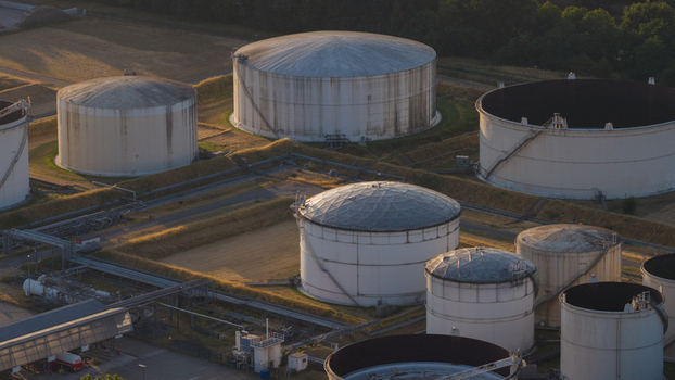 Aerial view of the Tanklager fuel storage facility with large white cylindrical tanks surrounded by earthen berms and industrial infrastructure in Hunxe North Rhine Westphalia Germany.