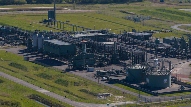 Aerial view of the NAM Grijpskerk UGS facility featuring industrial pipelines storage tanks and surrounding green fields in Grijpskerk Groningen Netherlands.