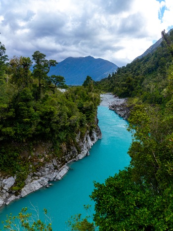 View of the stunning turquoise river snaking through a verdant gorge embraced by rugged rocks and dense forest under a dramatic sky Hokitika Gorge West Coast Region New Zealand. View of the stunning turquoise river snaking through a verdant gorge embraced by rugged rocks and dense forest under a dramatic sky Hokitika Gorge West Coast Region New Zealand.